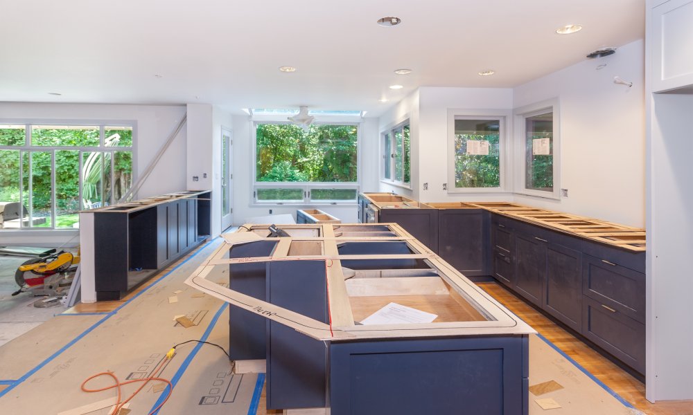 A large kitchen in the middle of a home remodeling project with coverings on the floor and no kitchen countertops yet.