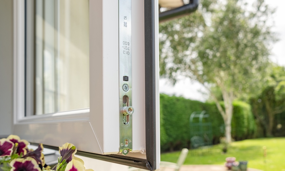 A close-up of a brand new window with multiple securing locks on its side. It's open and leading to the garden patio.