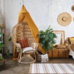 Natural Materials That Are Trending in Home Design A bohemian-inspired bedroom with natural materials and neutral colors. There's a hanging egg chair in the corner.
