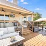 The Best Ways To Enjoy Sunny Days From Your Backyard A backyard deck with a wooden table and a couch with gray cushions. It is a bright, partly cloudy day.