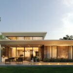 Pros and Cons of Choosing a Flat-Roofed Home A long shot of a luxurious flat-roofed home with warm lighting illuminating its exterior walls and landscaping.