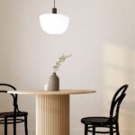 A breakfast nook with a round wooden dining table and black chairs. There's a pendent light hanging over the table.