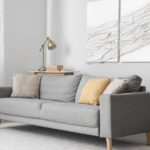 The interior of a luxury home with a gray sofa. Hanging on the wall are two pieces of textured wall art.